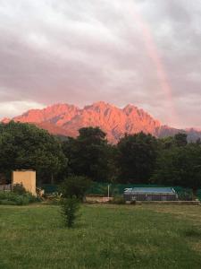 un arcobaleno sopra una montagna con un treno in un campo di Le coin tranquille a Morosaglia