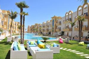 ein Resortgarten mit Sofas und einem Pool mit Palmen in der Unterkunft GHS app in Akouda