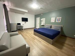 um quarto com uma cama azul e um sofá em Baansuay Rattanathibet Apartment em Nonthaburi