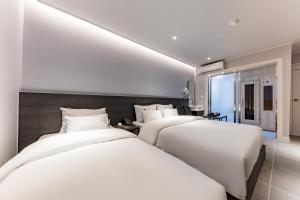2 Betten in einem Hotelzimmer mit weißer Bettwäsche in der Unterkunft Hotel the Rest in Cheongju