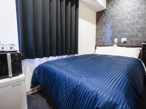 姫路市にあるHOTEL LiVEMAX 姫路市役所前のベッドルーム(青いベッド1台、黒いカーテン付)