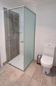 a shower stall in a bathroom with a toilet at Bells Beach Cottages - Pet friendly cottage with wood heater in Torquay