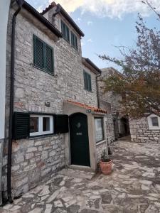 an old stone house with a green door at Charming Traditional Townhouse - Holiday Home Kata in Jezera
