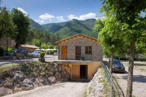 una pequeña casa con montañas en el fondo en Camping L'Espelt, en La Pobla de Lillet