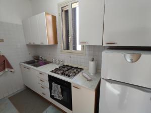 una cucina con piano cottura e frigorifero bianco di CASA DEL BORGO a Donnalucata