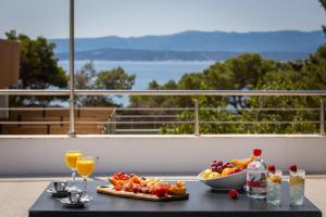 a table with a bowl of fruit and glasses of wine at Zlatni Rat Beach Resort in Bol