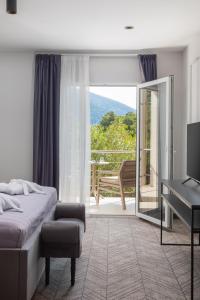a bedroom with a bed and a desk and a balcony at Zlatni Rat Beach Resort in Bol +37 photos