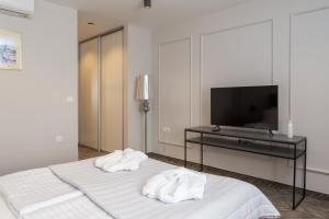 a bedroom with two white towels on a bed with a television at Zlatni Rat Beach Resort in Bol