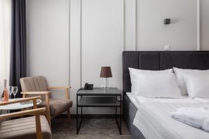 a bedroom with a bed and a chair and a side table at Zlatni Rat Beach Resort in Bol