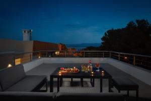 a patio with a table on a balcony at night at Zlatni Rat Beach Resort in Bol