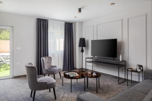 a living room with a tv and a couch and chairs at Zlatni Rat Beach Resort in Bol