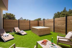 a backyard with a hot tub and chairs on grass at Zlatni Rat Beach Resort in Bol