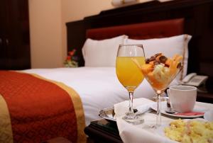 una habitación de hotel con una bandeja de comida y bebidas en una cama en Hotel Princesa, en Lima