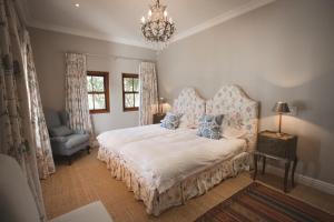 a bedroom with a bed and a chair and a chandelier at Lombard Villa in Plettenberg Bay