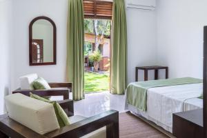 a bedroom with a bed and a chair and a window at Villa Sarakkuwa in Pamunugama