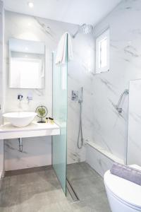 ein weißes Bad mit einem Waschbecken und einer Dusche in der Unterkunft Ninetta's Studios in Poros