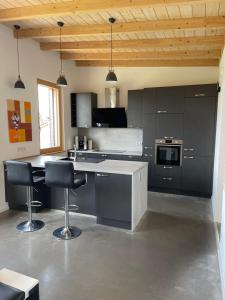 uma cozinha com armários pretos e bancos pretos de bar em Haus am See em Calden