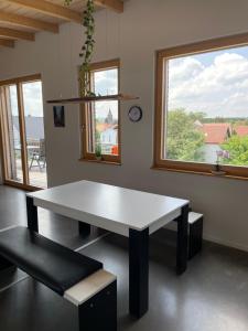 a white table and bench in a room with windows at Haus am See in Calden