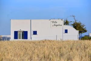 a white building with a sign on it next to a field at Villa Angelica in Perivolos