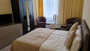 a bedroom with a bed and two chairs and a television at BASILICO Genova in Genova