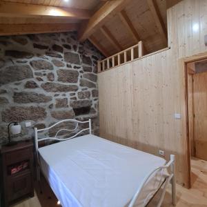 Cama en habitación con pared de piedra en Isatour - Casa do Miradouro, en Adsamo