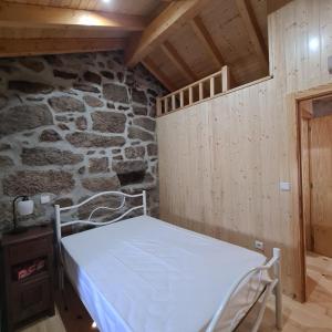 un letto in una stanza con un muro di pietra di Isatour - Casa do Miradouro a Adsamo
