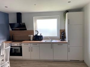 a kitchen with white cabinets and a sink and a window at Casa Cremer 1&2 in Übach-Palenberg