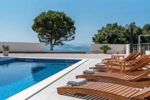 a swimming pool with two lounge chairs next to a house at Villa Helena in Trogir