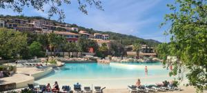 een groot zwembad met mensen in stoelen in een resort bij Maison 20 du Lac Les Restanques in Grimaud
