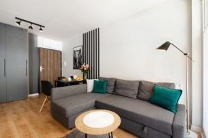 a living room with a gray couch and a table at Apartament Jarzębinowy z ogródkiem in Łódź