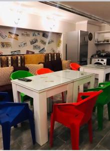 a kitchen with a white table and colorful chairs at Hostel VOYAGE in Batumi