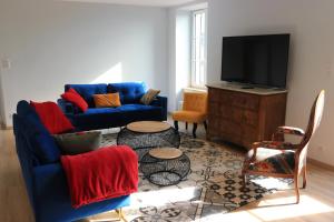 a living room with a blue couch and a tv at Le gîte de la glycine in Palmas