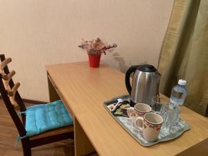 Комфортабельная комната в квартире في أستانا: طاولة مع صينية مع غلاية الشاي وأكواب عليها