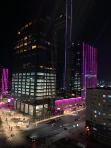 uma cidade à noite com edifícios com luzes roxas em Комфортабельная комната в квартире em Astana