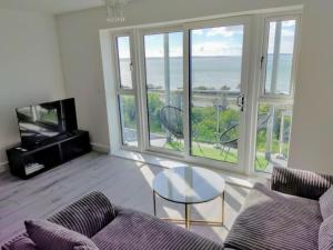 a living room with a couch and a table at Modern apartment with breathtaking sea views in Penmaen-mawr