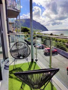 une chaise sur un balcon avec vue sur l'océan dans l'établissement Modern apartment with breathtaking sea views, à Penmaen-mawr