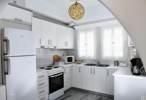 a white kitchen with white cabinets and a chandelier at Villa Angelica in Perivolos
