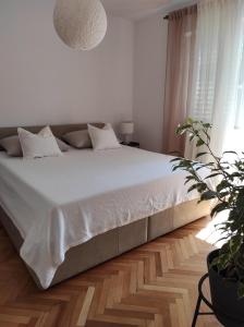 a bedroom with a bed with white sheets and a potted plant at Apartman Maja in Vodice