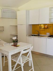 a kitchen with white cabinets and a white table and chair at La Terrazza nel Mare in Acciaroli