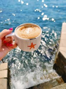 a person holding a cup of coffee near the water at Apartments Villa PM in Kotor