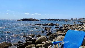 una silla azul sentada en una playa rocosa en La Terrazza nel Mare en Acciaroli