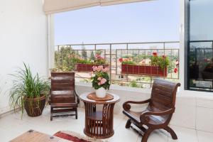 ein Zimmer mit 2 Stühlen und einem Tisch mit Blumen im Fenster in der Unterkunft Kfar Saba View Apartment in Kfar Saba