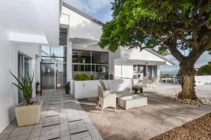 a white house with a tree and a patio at Capo Cabana Guesthouse in Plattekloof