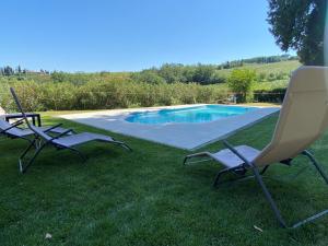 two chairs sitting in the grass near a swimming pool at Il Castagnolo B&B in San Gimignano