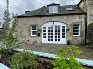 a stone house with a white door at Charming Barn Conversion on Private Estate in Symington