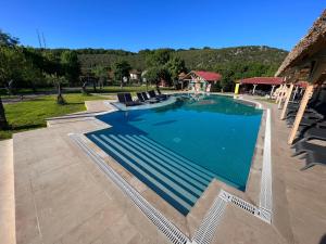 a large swimming pool with chairs and a house at Dachas Cove Hotel in Agva