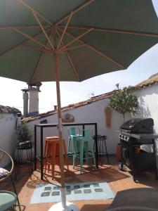a green umbrella on a patio with chairs and a grill at Maison de village familiale Pont du Gard, toit terrasse, barbecue, Fibre in Vers Pont du Gard
