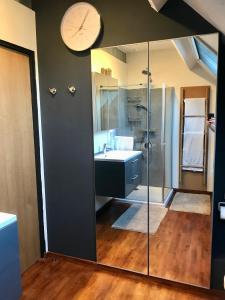 een badkamer met een wastafel, een douche en een klok bij Chambre d'hôte Saint-Symphorien Mons in Bergen