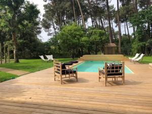 two chairs sitting on a wooden deck next to a pool at Villa Sophie in Lanton