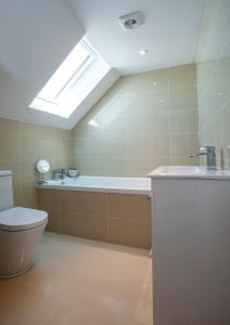 a bathroom with a tub and a toilet and a skylight at WESTBROOK HOUSE, BAYSIDE in Kent